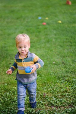 Paskalya yumurtası taşıyan küçük bir çocuk yumurta avında..