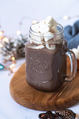 Cam bardakta marşmelovlu kakao içeceği, hafif mermer bir masada servis edilir ve Noel süsleri ile servis edilir. Kış havası. Yakın plan. Seçici odak