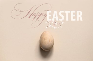 Tarafsız pastel arka planda bir Paskalya yumurtası. Minimalist düz kompozisyon. Mutlu Paskalyalar yazılı tebrik kartı. Modern Moda Paskalya Üst Kompozisyonu