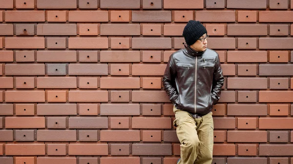 Un hombre asiático con una chaqueta marrón se apoya contra la pared — Foto de Stock
