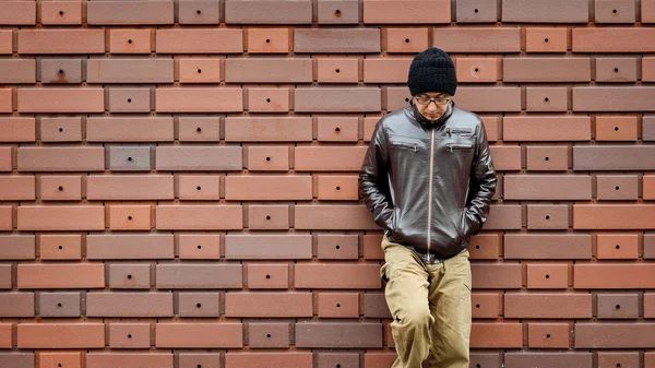 Un hombre asiático con una chaqueta marrón se apoya contra la pared — Foto de Stock