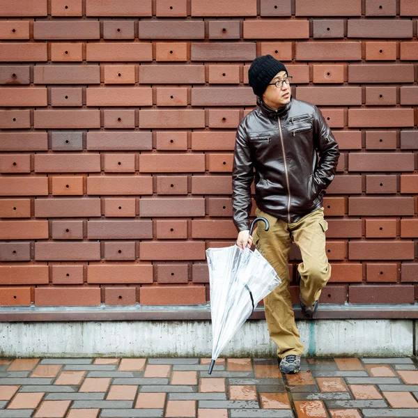 Un hombre asiático en una chaqueta marrón con un paraguas claro — Foto de Stock