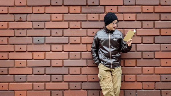 Un hombre asiático en una chaqueta marrón con un cuaderno pequeño — Foto de Stock