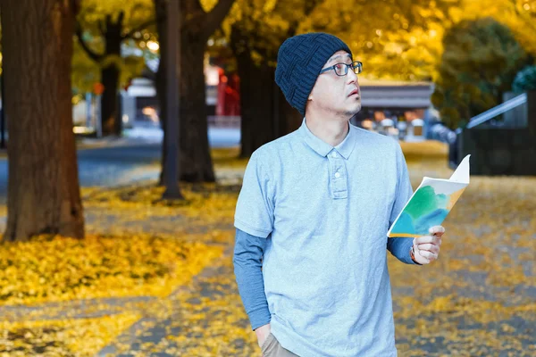 En asiatisk man i en polo t-shirt med ginkgo träd i höst — Stockfoto