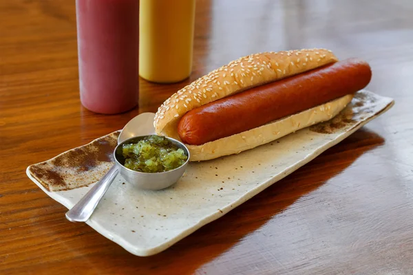 Hotdog com uma salsicha grande em uma placa em uma mesa — Fotografia de Stock