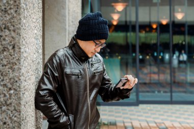 Asyalı bir adam onun Smartphone ile kahverengi ceket