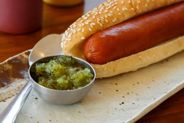 Hotdog com uma salsicha grande em uma placa em uma mesa — Fotografia de Stock