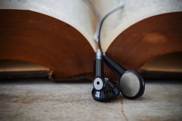 Earphones hung on an opened book — Stock Photo, Image