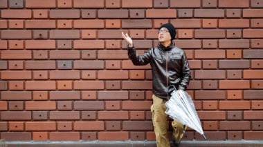 Açık bir şemsiye ile kahverengi ceketli Asya bir adamı