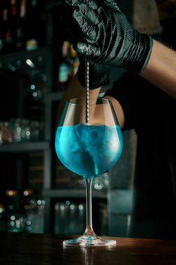 Barmen alkollü bir kokteyl hazırlıyor. Barda buzlu güzel bir bardağa sıvı karıştırmak. Bar aksesuarları