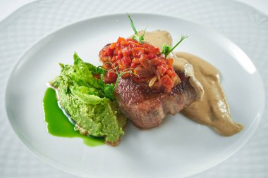 Domates salsa soslu domuz eti, mantar sosu ve beyaz tabakta bezelye püresi. Yaklaş, seçici odaklanma