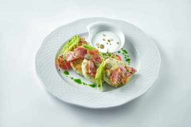 Lezzetli kahvaltı. Beyaz arka planda beyaz bir tabakta domuz pastırmalı ve ekşi kremalı peynirli kek. Syrniki.