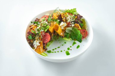 İştah açıcı ve diyet salatası kavrulmuş kabak roka, beyaz arka planda beyaz tabakta feta ve domates..