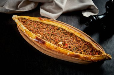 Kuzu kıymalı Türk pidesi, domates, siyah arka planda dolma biber.