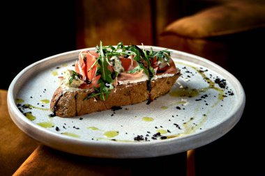 Prosciutto, gorgonzola ve çavdar ekmekli roka, beyaz tabakta servis edilir. Restoran yemeği. Yukarıdan bak. İtalyan mutfağı