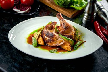 Beyaz bir tabakta servis edilen patates püresi ve avakodolarla süslenmiş sarı ve yeşil soslu kızarmış tavuk butları. Restoran yemeği. Et yemeği.