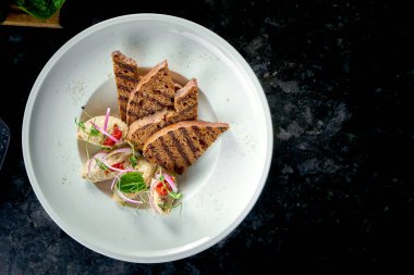 Klasik İsrail mutfağı yemeği. Misket arka planında beyaz bir tabakta sunulan kızarmış ekmekli ringa balığı. Deniz ürünleri..