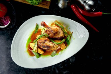 Beyaz bir tabakta servis edilen patates püresi ve avakodolarla süslenmiş sarı ve yeşil soslu kızarmış tavuk butları. Restoran yemeği. Et yemeği.