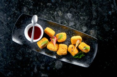 Koyu arkaplanda siyah bir tabakta servis edilen reçelli peynirli krema kızartması. Restoranda atıştırmalık. Yemek barı.