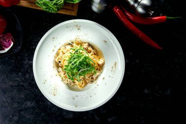 İştah açıcı İtalyan makarnası, yabani mantarlar ve beyaz sosla birlikte koyu mermer arka planda beyaz bir tabakta servis ediliyor. İtalyan spagettisi. Restoran yemekleri.