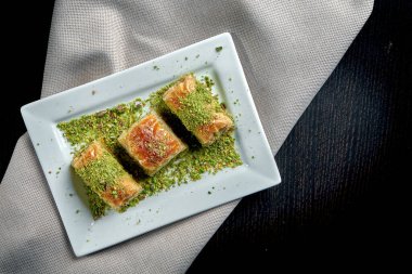 Klasik Türk tatlıları, ballı baklava ve beyaz tabakta puf böreğinden fıstık. Yaklaş, seçici odaklanma