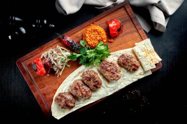 Tahta bir tahtanın üzerinde kuzu pirzola ve mangalda sebzeyle yapılan iştah açıcı Türk pirzolası.