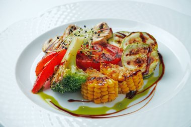 Sağlıklı meze - ızgara sebze, mısır, domates, kabak ve brokoli beyaz tabakta servis edilir. Yaklaş, seçici odaklanma