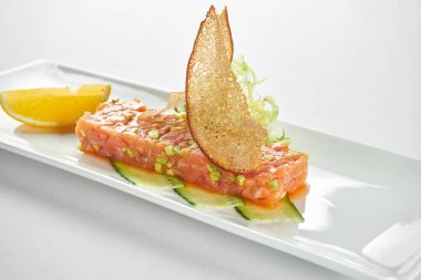 Lezzetli aperatif. Avokado ve siyah havyarlı somon tartar. Mavi masa örtüsü üzerinde beyaz bir tabakta..