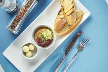 İdeal bir aperatif - karamelli soğanlı tavuk ciğeri ezmesi ve beyaz arka planda beyaz bir tabakta çavdar ekmeği.