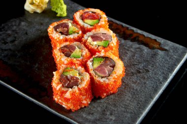 California suşisi, ton balığı, avokado, salatalık ve tobiko havyarla birlikte wasabi ve zencefil ile servis edilir. Siyah arka planda izolasyon. Japon yemeği.