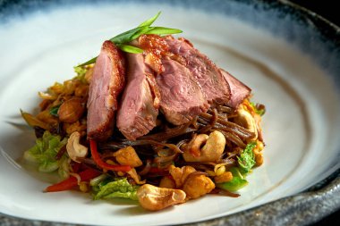 Ördekli, fıstıklı, sebzeli ve soğanlı karabuğday eriştesi, beyaz bir kasede servis edilir. Yumurtalı erişte. Siyah arka planda izole edilmiş. Sokak Tayland yemeği