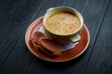 Geleneksel Fas çorbası - Harira, siyah ahşap arka planda kırmızı tabakta kişniş içeren sarı mercimek çorbası. Diyet çorbası.