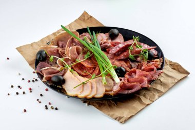 Çeşitli İtalyan etleri, jambon, biftek, salam, jambon, prosciutto ve siyah bir arka planda bej bir tabakta sucuk. Antipasti