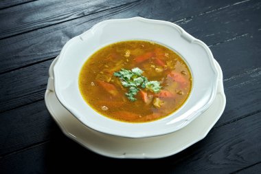 Yakın plan Chorba çorbası ya da biftek, ot ve ahşap arka planda beyaz kasede acı biber, geleneksel Türk mutfağı.