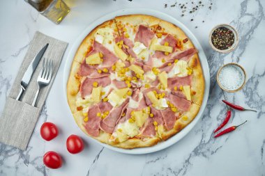 Lezzetli ve çıtır çıtır İtalyan pizzası, jambon, ananas ve mısır, mermer bir tabakta beyaz sos. Üst manzara pizzası