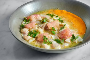 Peru mutfağı tabağı - greyfurt ve sarı soslu deniz kabuğu ceviche, mermer arka planda gri bir tabakta servis ediliyor. Restoran deniz ürünleri..