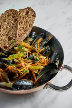 Kabuklu midye. Sebzeli midye. Beyaz mermer arka planda kızarmış ekmek.