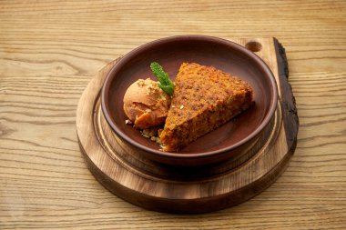 Ahşap arka planda kil kasede elmalı dondurma ile iştah açıcı havuçlu kek. Sağlıklı bir tatlı. Hamur işi