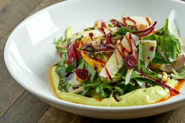 Avokado soslu vejetaryen salata kasesi, parmesan peyniri, ıspanak, böğürtlen sosu ve ahşap arka planda pişmiş elmalar. Sağlıklı ve besleyici yiyecekler.