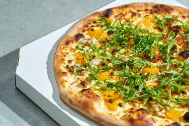 Krema soslu iştah açıcı pizza, tavuk, sarı domates, kapari. Kıtır kıtır. Sert ışık. Gri arkaplan.