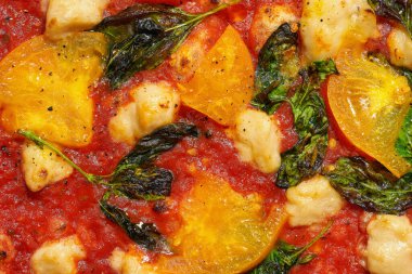 Lezzetli İtalyan ahşabı domates soslu pizza, sarı domates ve gri arka planda vegan peyniri. Sert ışık.