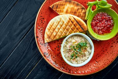 Geleneksel İsrail ya da doğulu Baba ghanoush sebze salsa ve pita ile koyu arka planda kırmızı bir tabakta servis edilir. Patlıcan lokantası yemeği