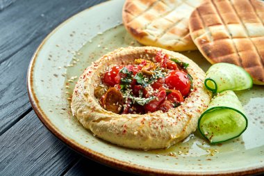 Klasik bir doğu yemeği - fırında domates ve nohut yağlı humus. Koyu ahşap bir arka planda fırında pide servis ediliyor. Vejetaryen yemeği. Diyet