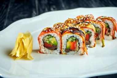 Sebzeli suşi rulo sebze, havuç, domates, salatalık ve avokado, siyah arka planda beyaz bir tabakta servis ediliyor. Japon mutfağı.