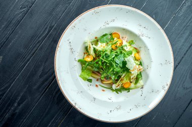 İştah açıcı, roka soslu diyet salatası, marul ve siyah ahşap arka planda beyaz tabakta sıcak et. Sağlıklı yemek.