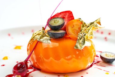 Lezzetli tatlı. Çilek dolgulu mango kreması ve beyaz tabakta karamel ve böğürtlen süsü. Gri arkaplanda izole.