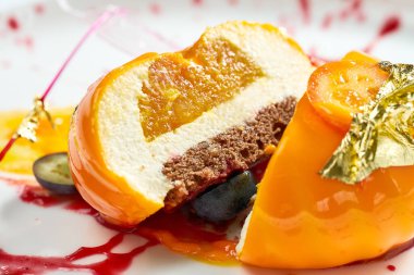 Lezzetli tatlı. Çilek dolgulu mango kreması ve beyaz tabakta karamel ve böğürtlen süsü. Gri arkaplanda izole.