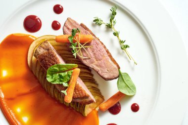 Armut ve sarı elma püresiyle iştah açıcı ördek göğsü, beyaz tabakta böğürtlen sosu. Gri arkaplanda izole.