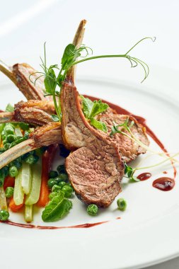 Sebze ve böğürtlen soslu ızgara kuzu eti. Beyaz arkaplanda gri.