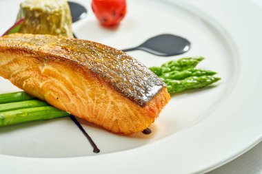 Beyaz tabakta ızgara somon bifteği, kuşkonmaz ve balzamik sos. Beyaz arka planda izole edilmiş. Yukarıdan görüntüle